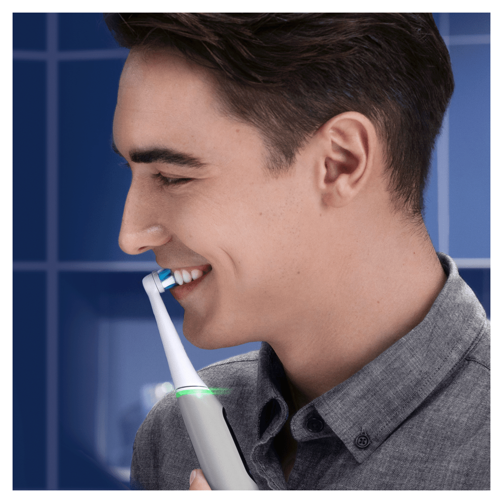 Hombre cepillándose los dientes con un cepillo blanco y azul.