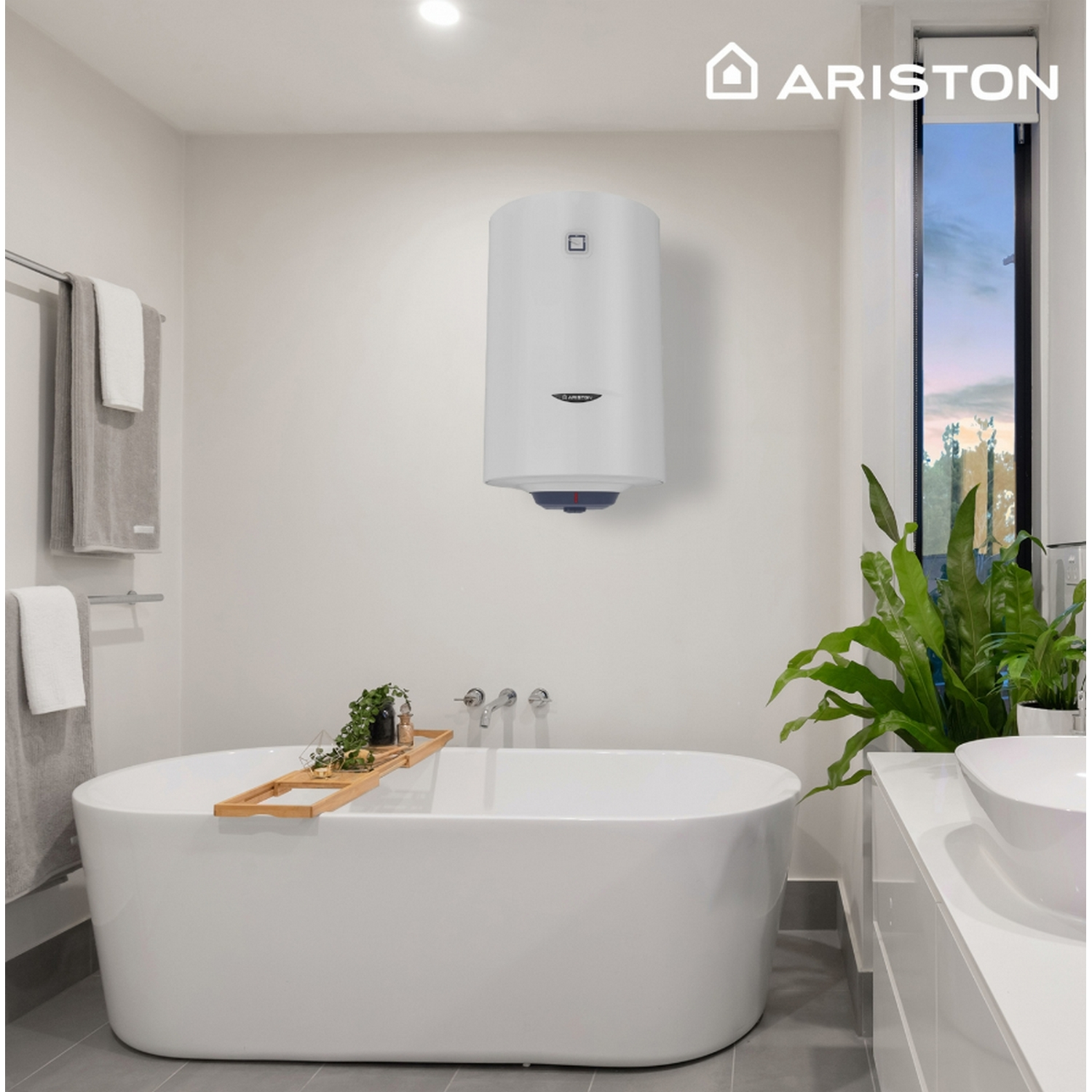 Baño blanco con bañera, planta y calentador de agua en la pared. El logotipo de la marca Ariston es visible.