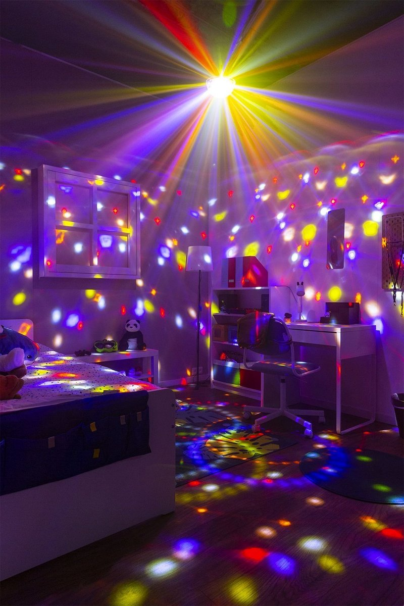 Chambre éclairée par des lumières colorées. Une fenêtre, un lit et un bureau sont visibles.