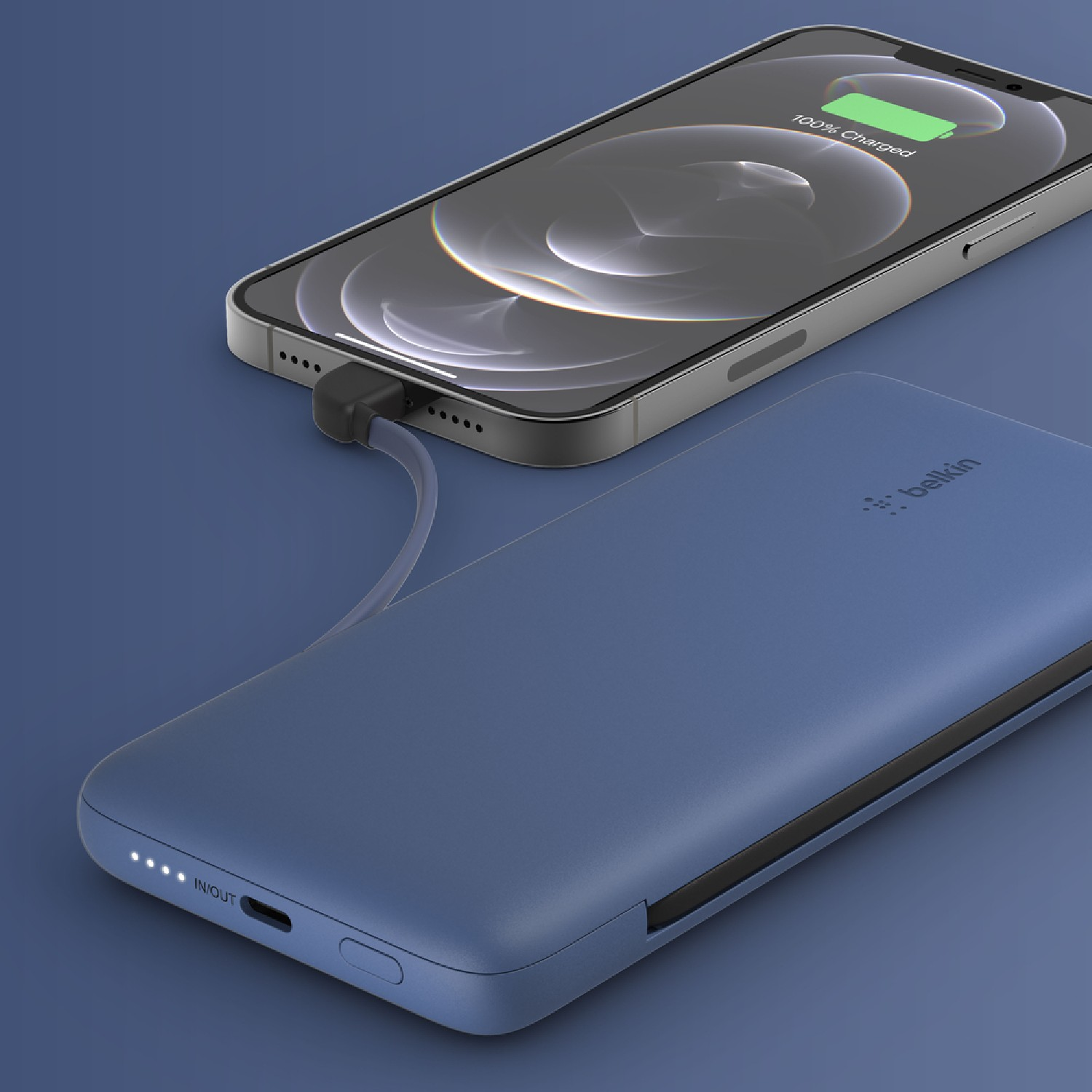 Un teléfono cargando de un banco de energía azul. El teléfono muestra 100% cargado. Fondo azul.