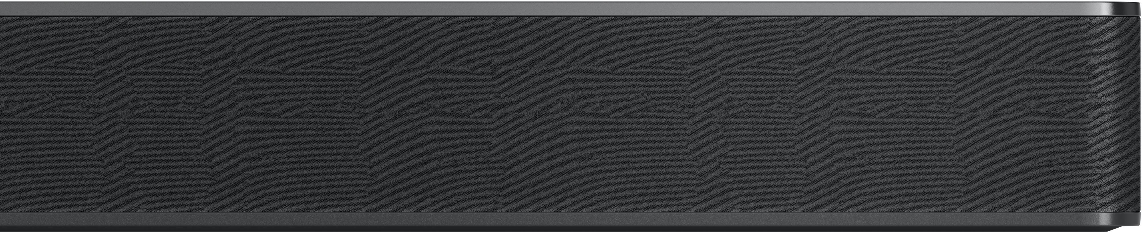Eine schwarze Soundbar mit dunkelgrauem Stoffbezug, die auf einer ebenen Fläche liegt.