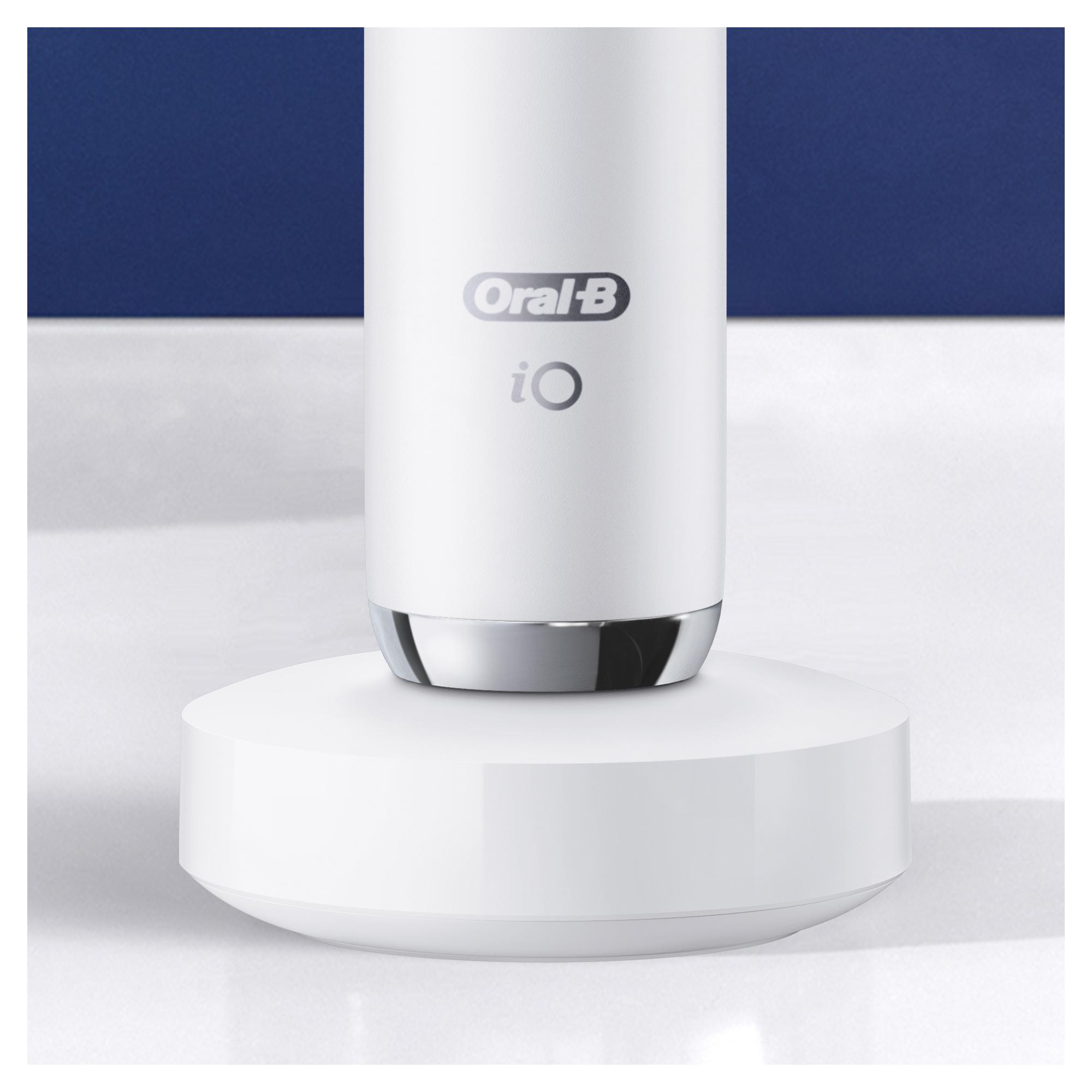 Eine weiße elektrische Zahnbürste Oral-B iO auf ihrer Ladestation, vor blauem Hintergrund.