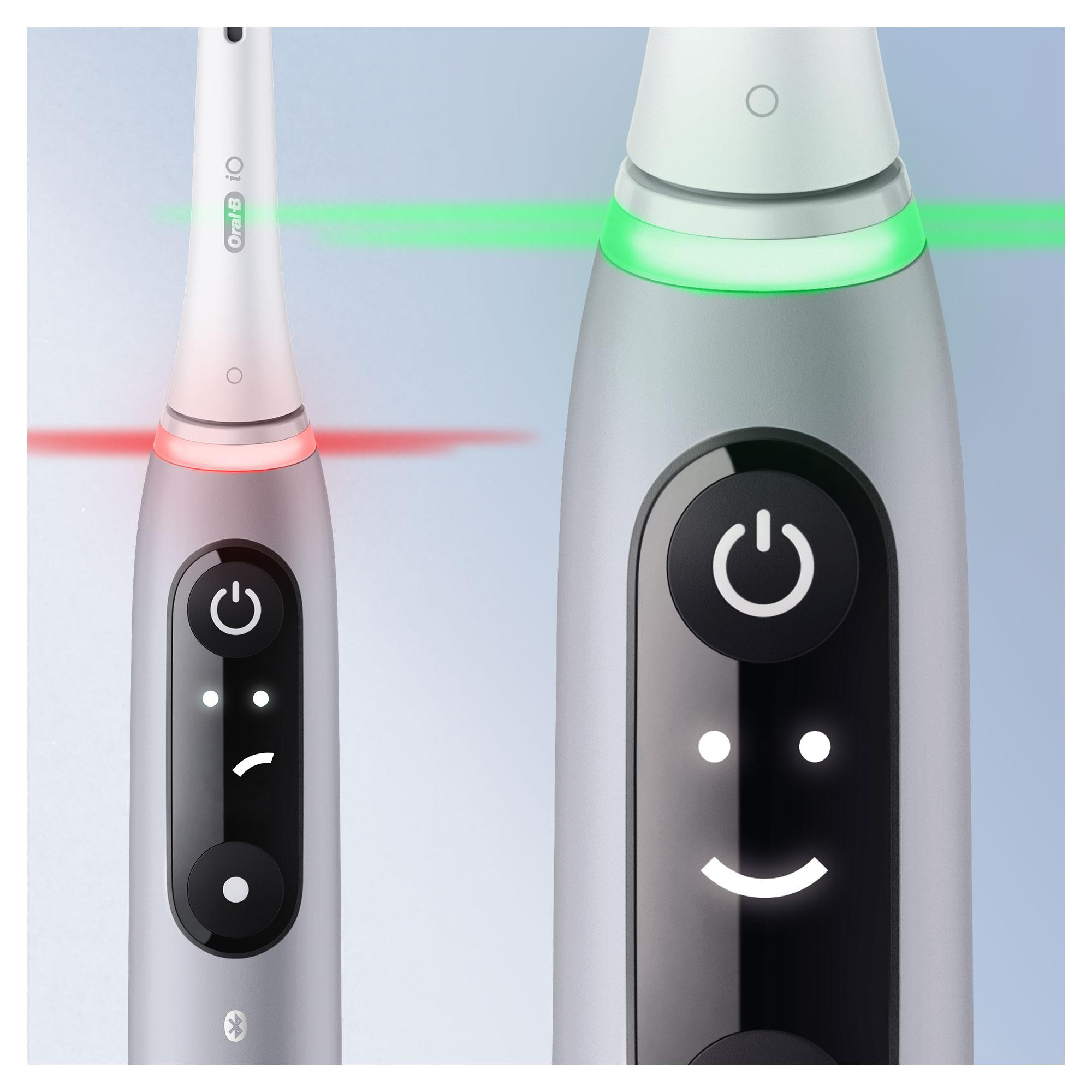 Nahaufnahme von zwei elektrischen Zahnbürsten, eine mit rotem Licht und eine mit grünem Licht.