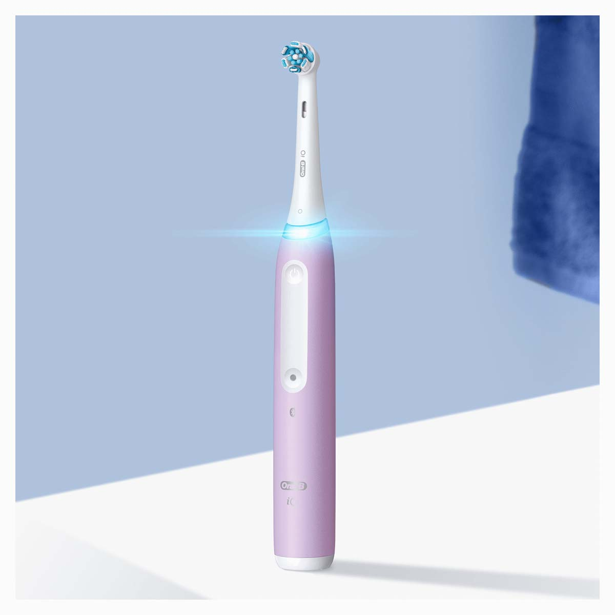 Brosse à dents électrique, violette et blanche. Lumière bleue allumée. Logo Oral B.
