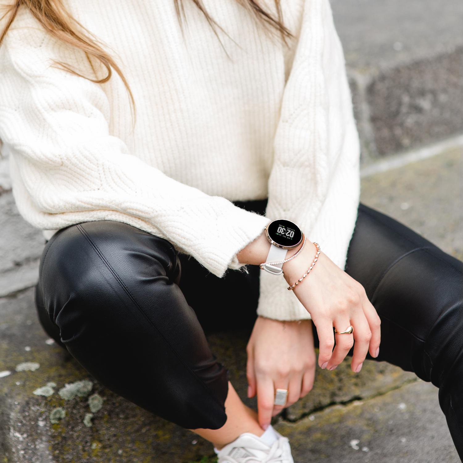 Frau mit weißem Pullover und Uhr mit Armband.