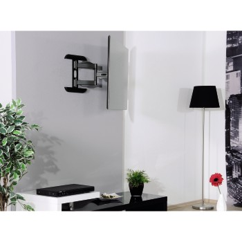 Un salón moderno con un televisor montado en la pared, una mesa negra, una lámpara y una flor roja.