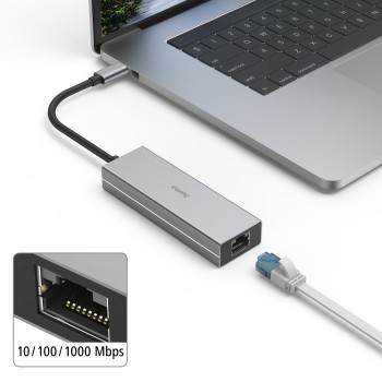 Un adaptador plateado conectado a un portátil con un cable negro y un cable ethernet blanco.