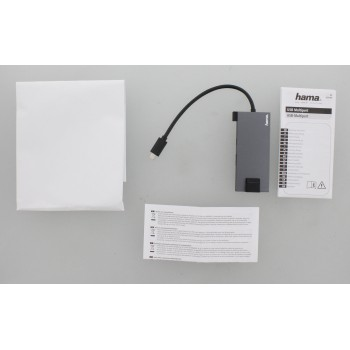 Concentrador USB con cable, papel blanco e instrucciones, sobre fondo gris.