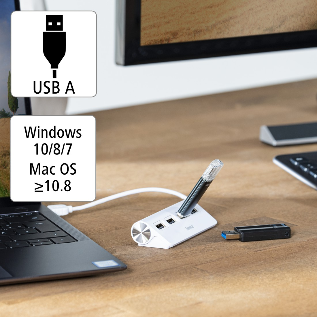 Un concentrador USB y una unidad USB en una mesa de madera. Un portátil y un monitor al fondo.