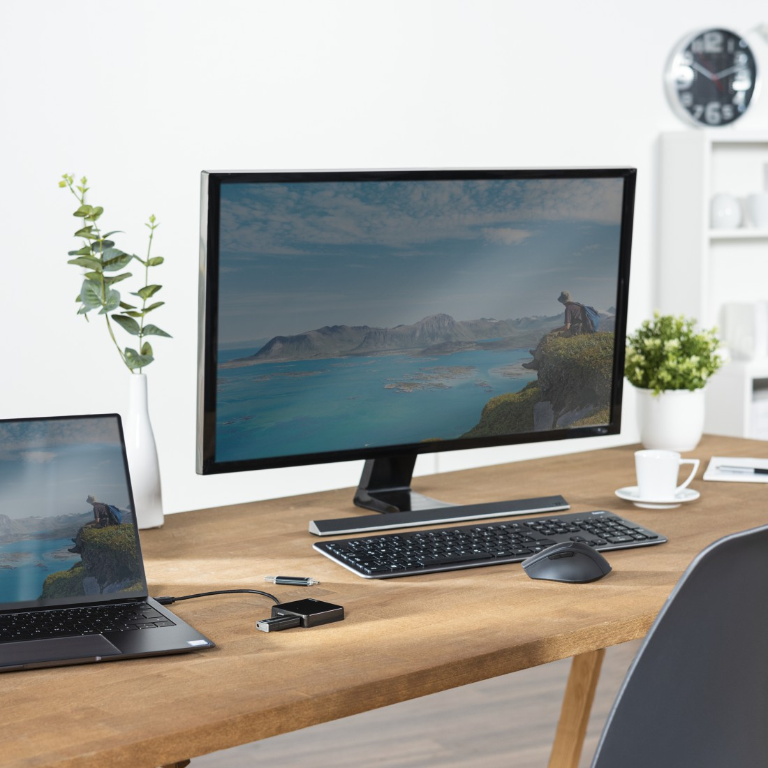 Laptop, monitor, teclado, ratón sobre escritorio de madera. Mostrando un paisaje costero.