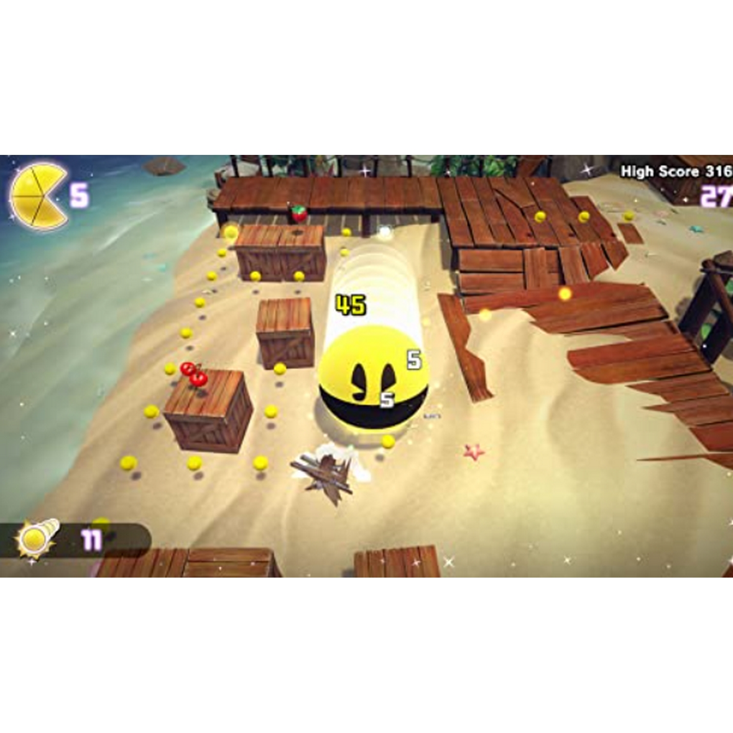 Una escena de videojuego. Un Pac-Man amarillo corre por un nivel arenoso. Hay cajas de madera y puntos.