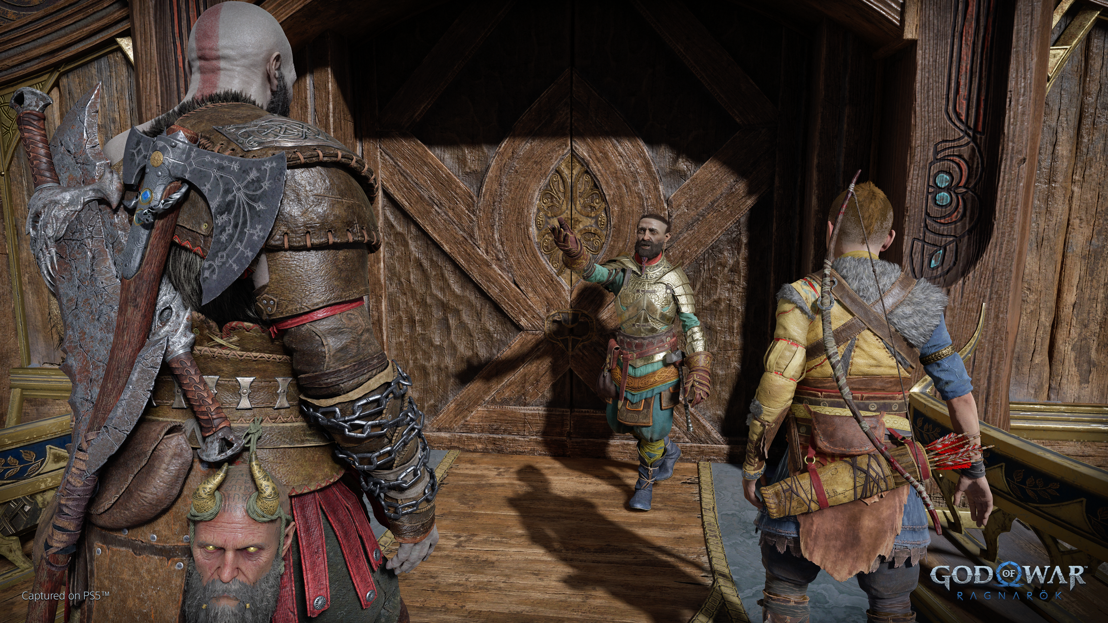Une scène de 'God of War: Ragnarok'. Kratos et Atreus sont dans une porte, un homme montre du doigt.