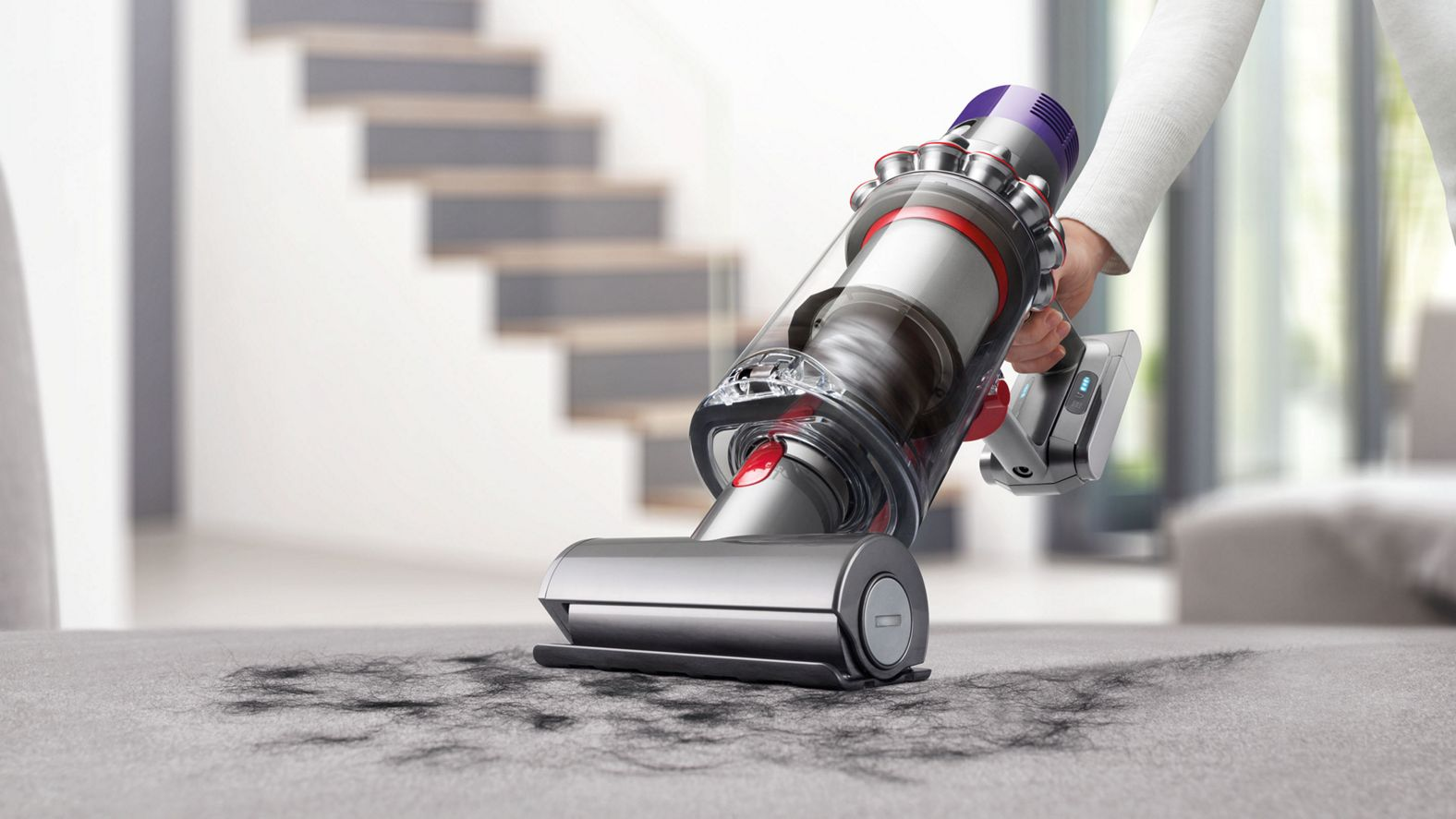 Ein Dyson-Staubsauger in Gebrauch auf einem Teppich, der Schmutz entfernt.