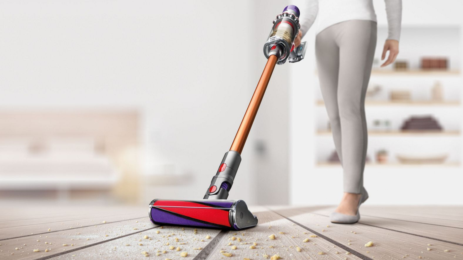 Eine Person saugt einen Holzboden mit einem rot-violetten Staubsauger.