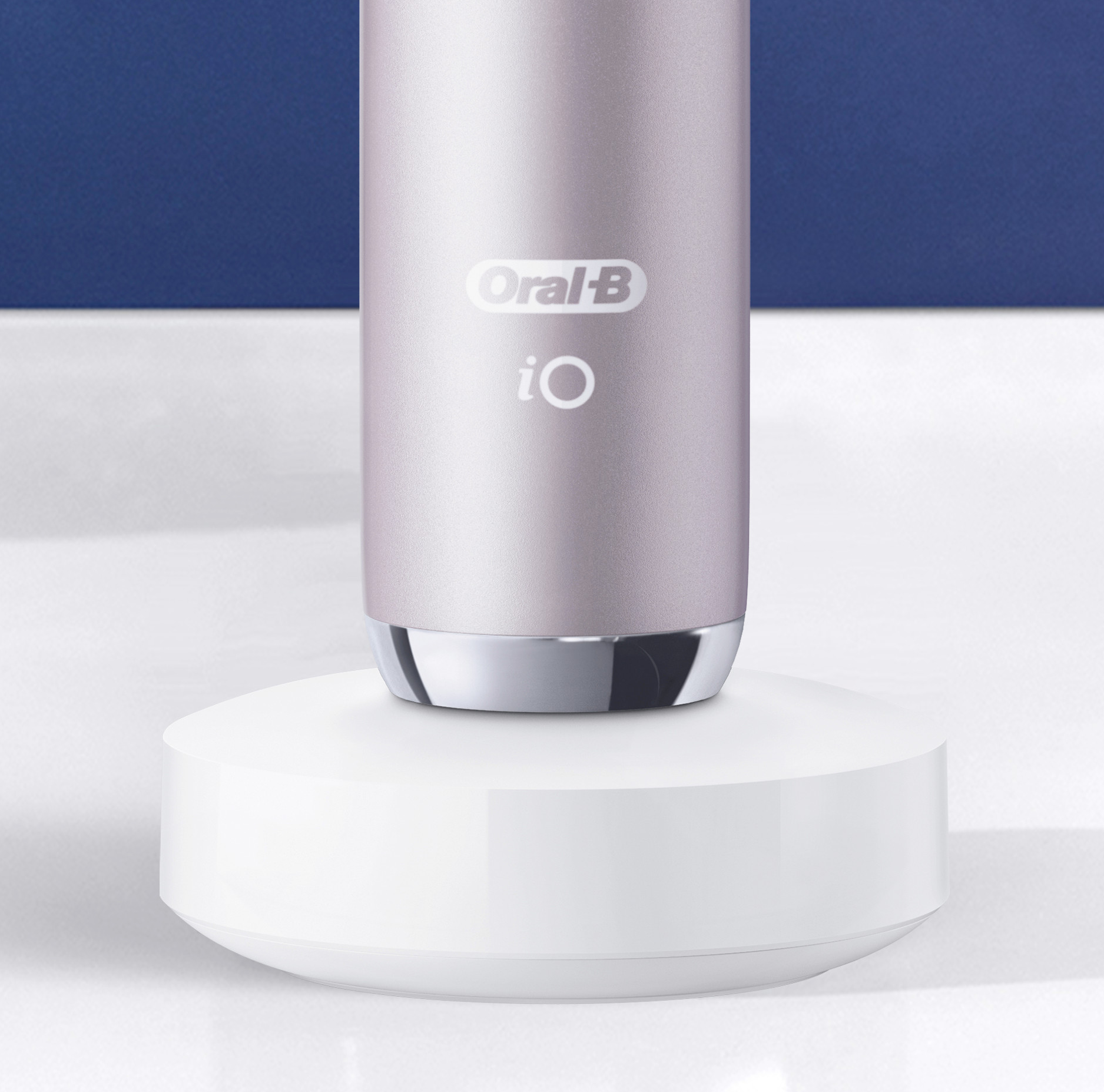 Primo piano di uno spazzolino Oral-B iO rosa su una base di ricarica bianca.