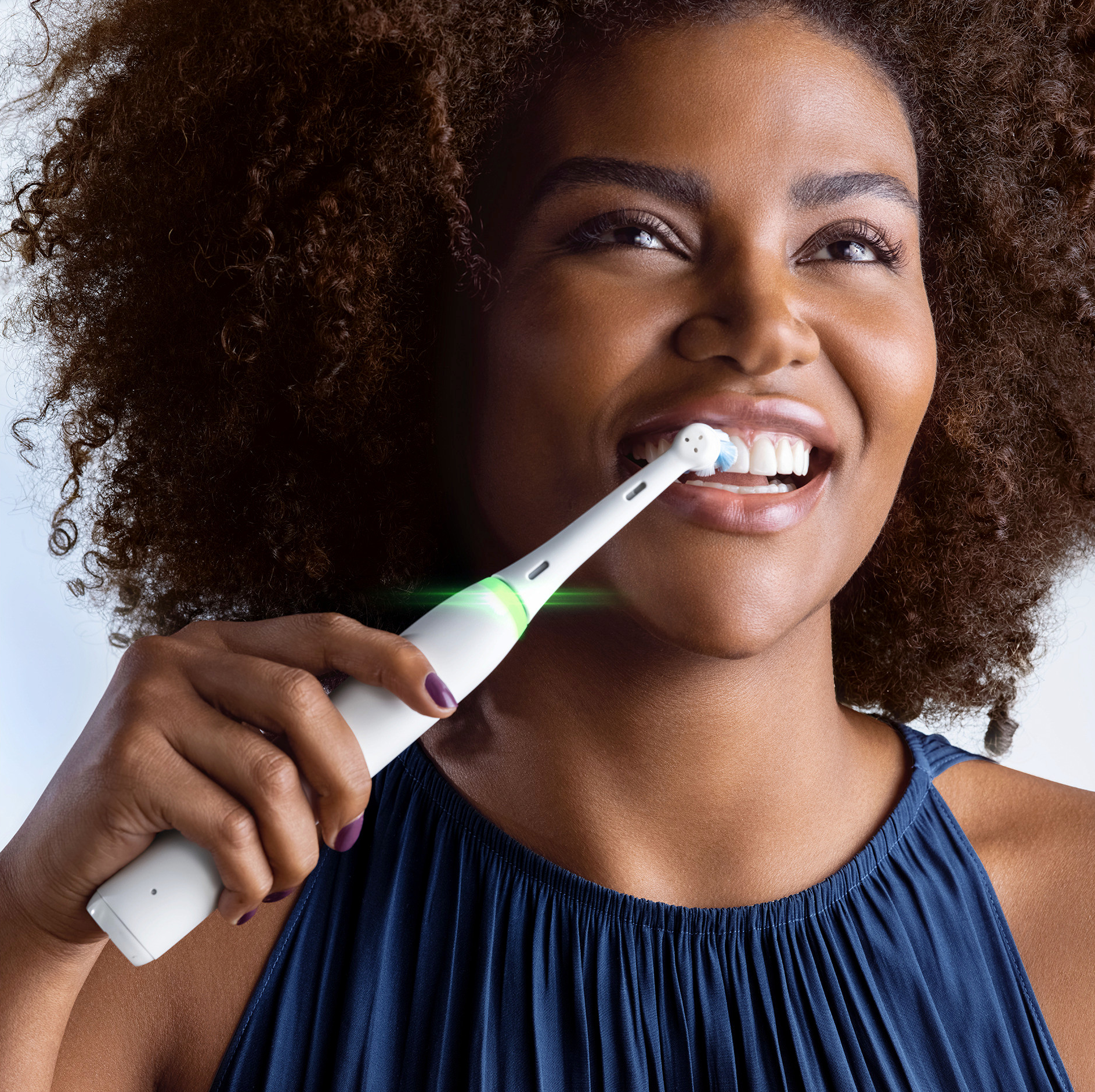 Donna che si lava i denti con uno spazzolino elettrico bianco, primo piano.