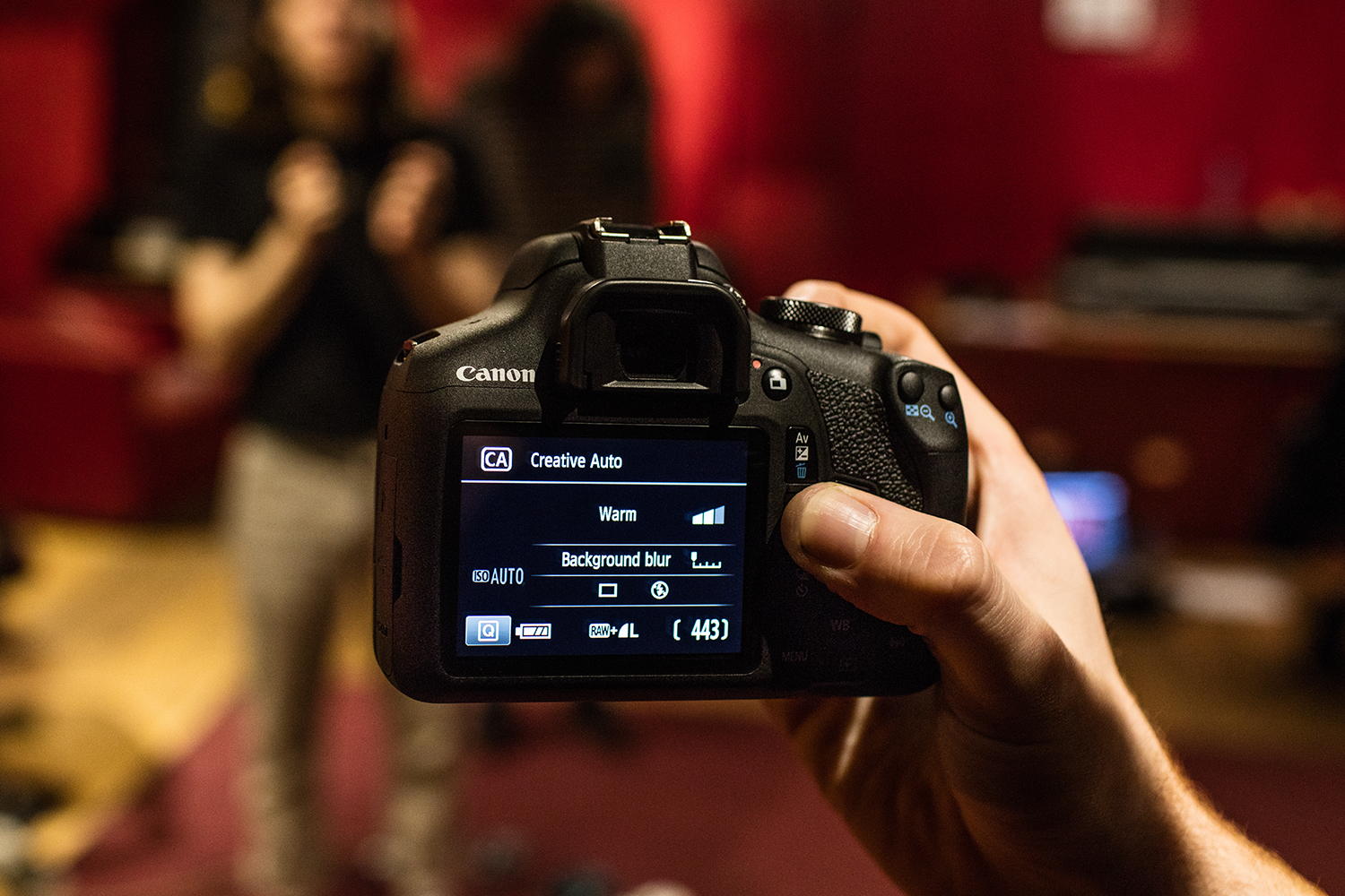 Persoon die een zwarte Canon-camera vasthoudt en het scherm toont.