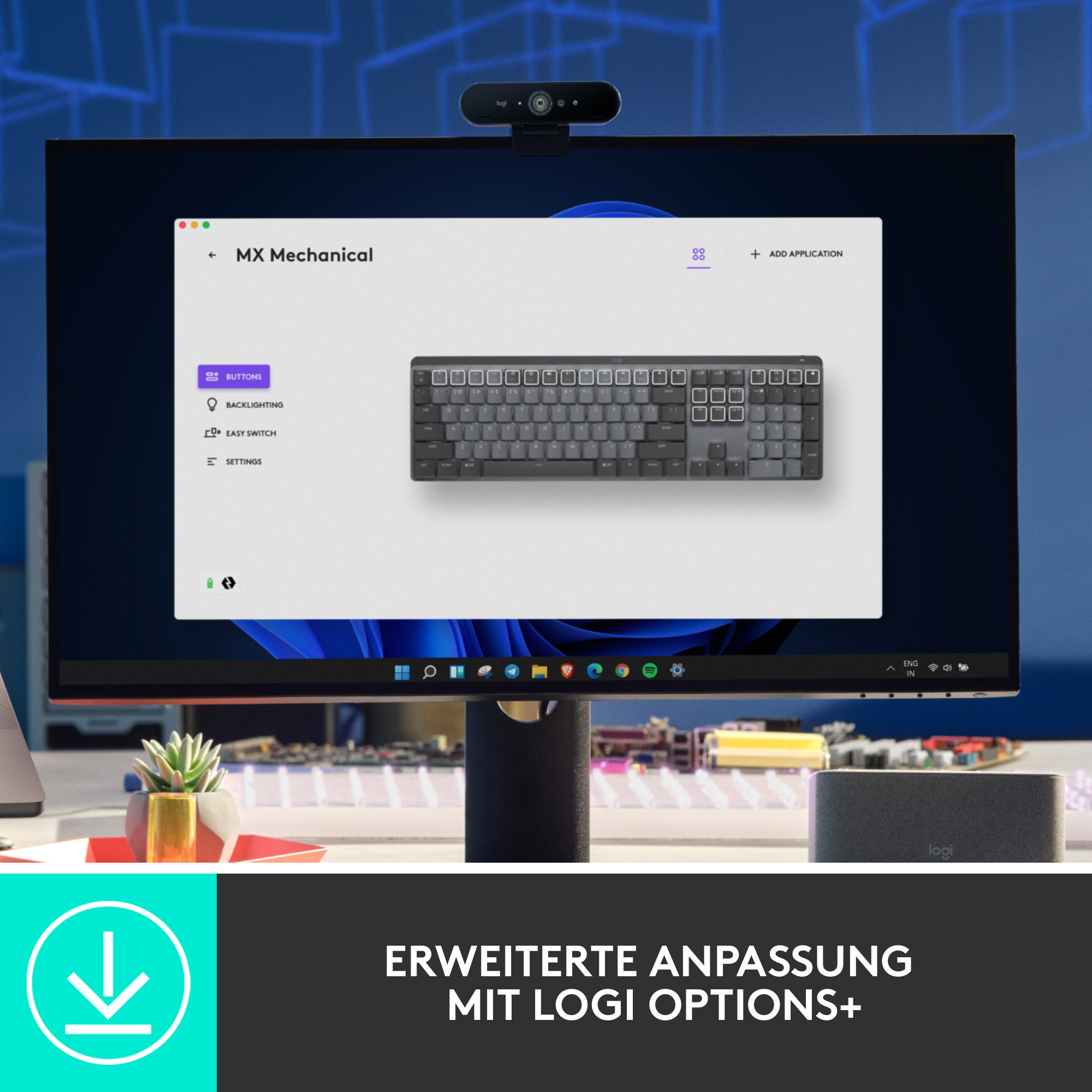 Ein Monitor mit angezeigter Tastatur, eine Kamera, eine Maus, eine Pflanze und ein Lautsprecher.