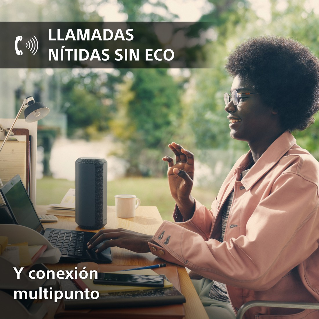 Una mujer está en videollamada. Un altavoz está en el escritorio. El texto dice 'Llamadas claras, sin eco'.