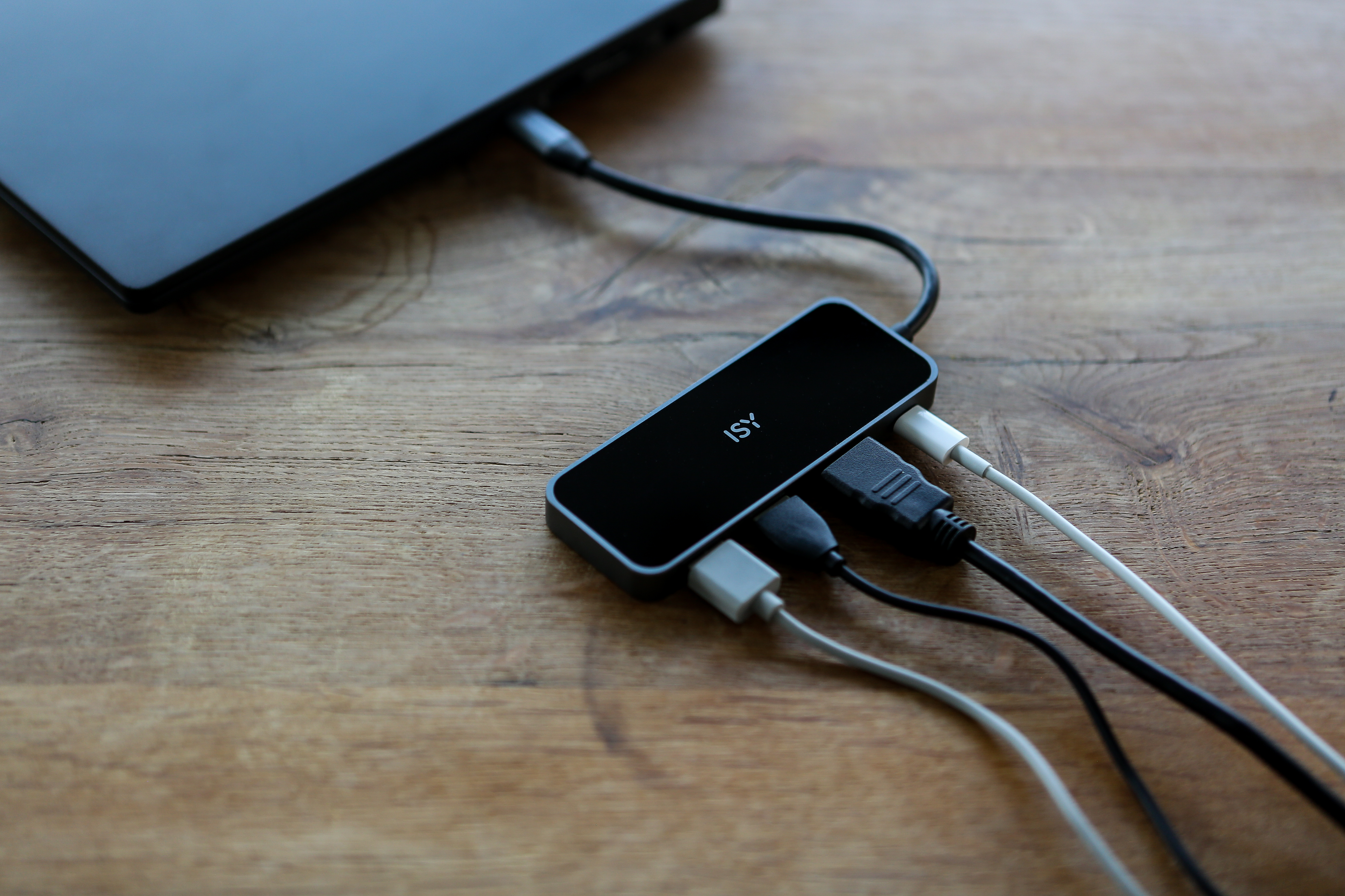 Schwarzer USB-Hub, angeschlossene Kabel, Holzoberfläche, Nahaufnahme.
