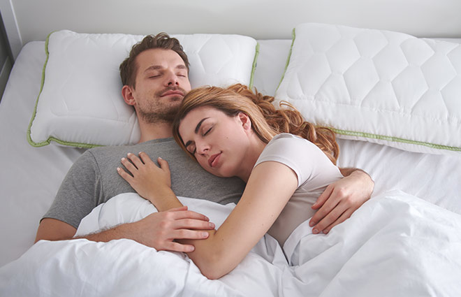 Egy pár alszik együtt az ágyban, ölelkeznek.