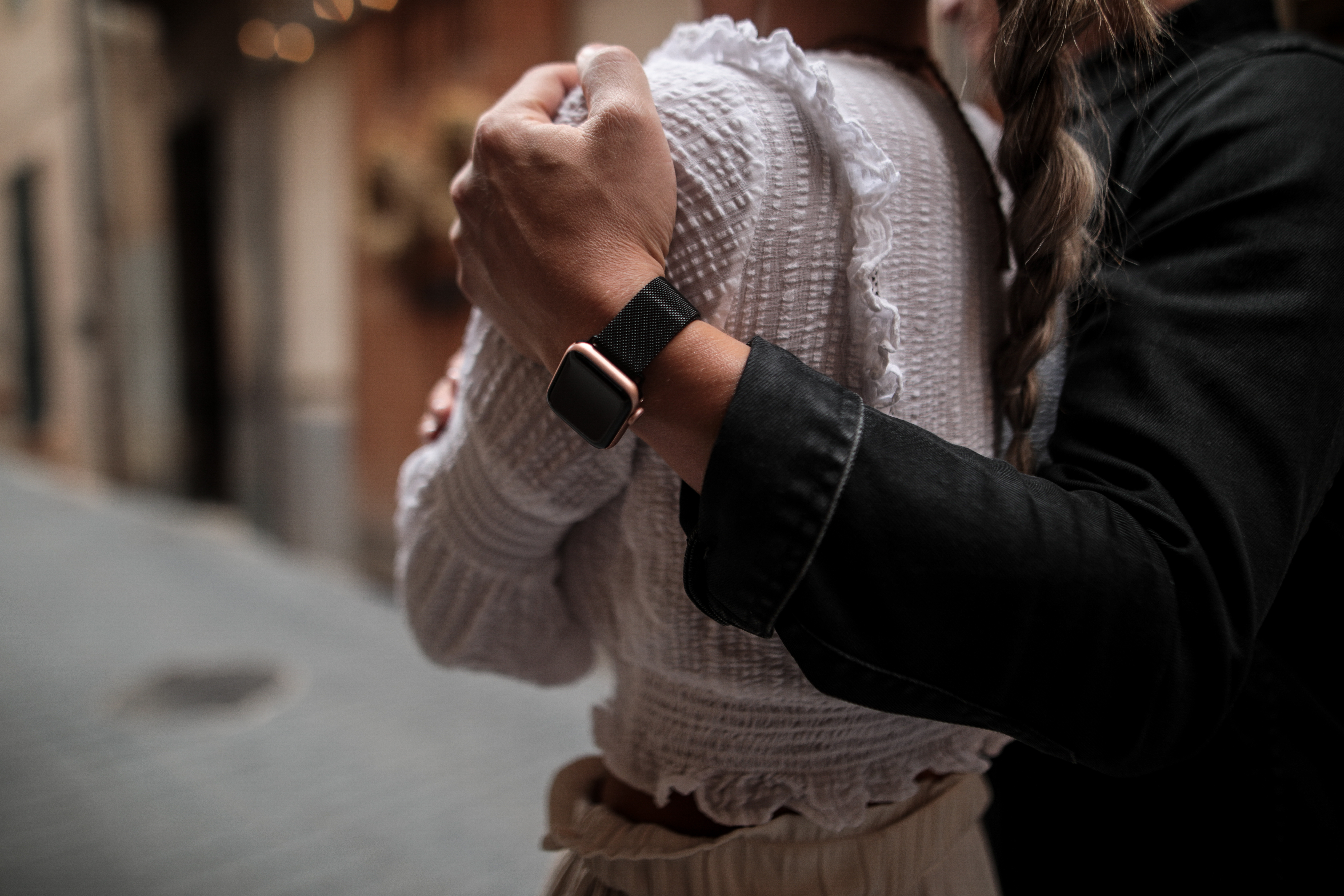 Die Hand einer Person auf der Schulter einer anderen, eine Uhr sichtbar.