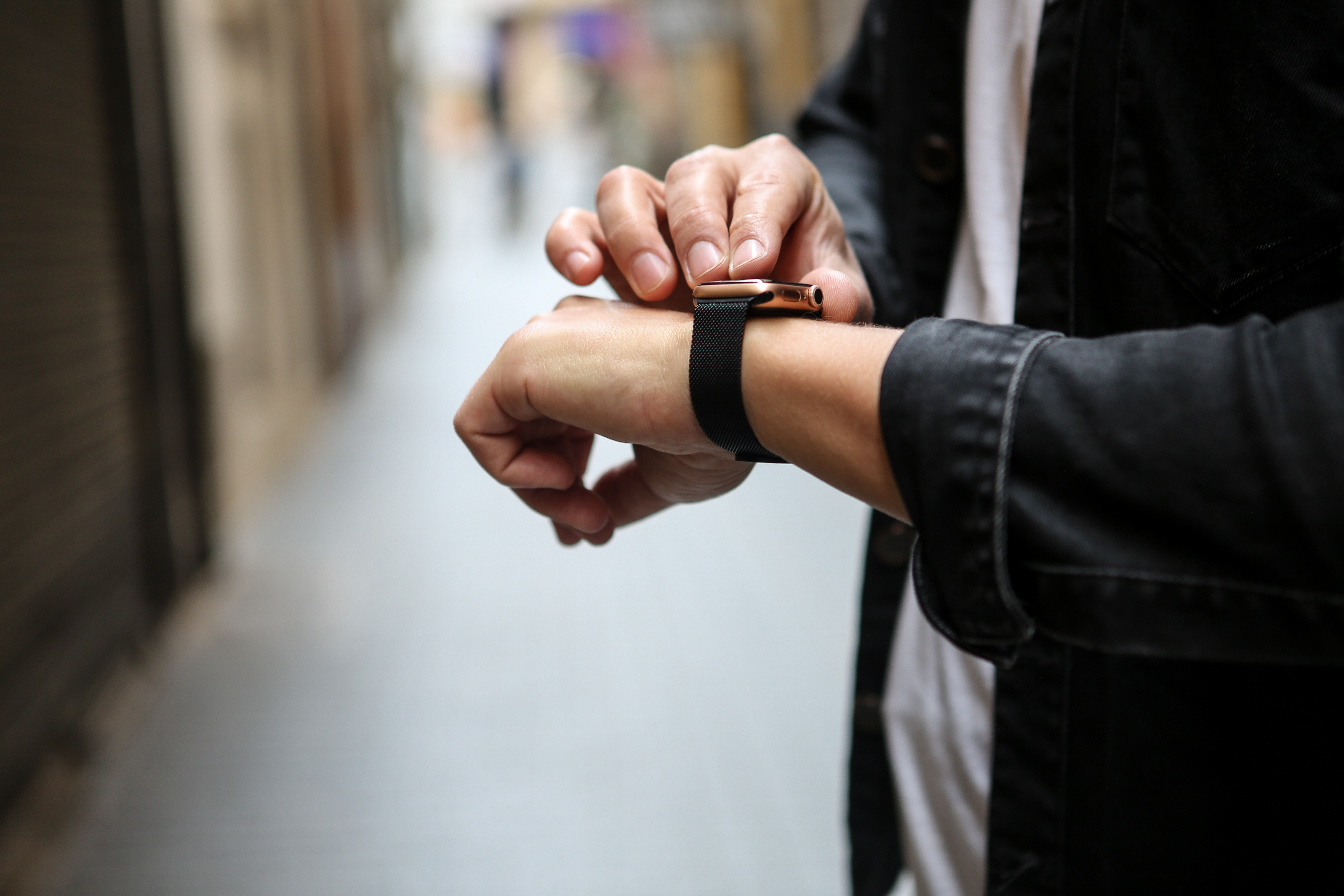 Eine Person checkt ihre Smartwatch am Handgelenk in einer Straßenszene.