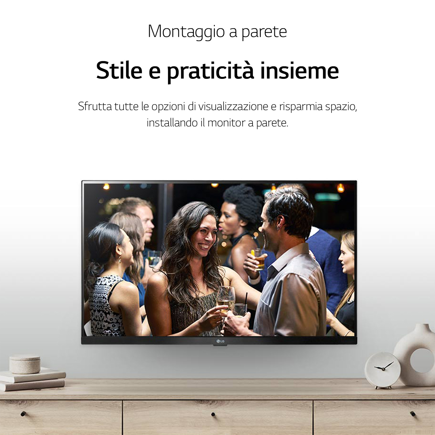 Un televisore che mostra una scena di festa è su un mobile in legno, con un vaso e un orologio.