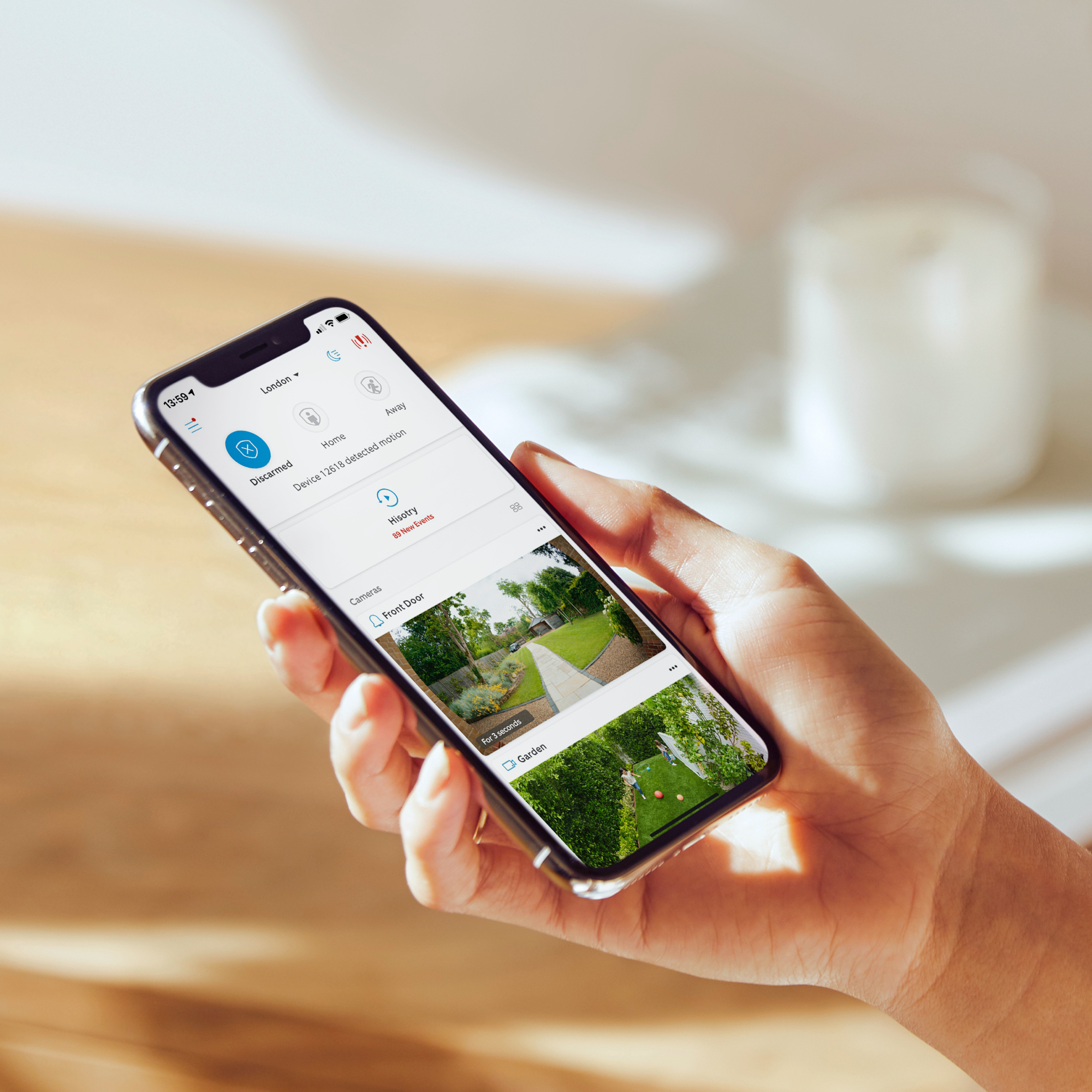 Een hand die een smartphone vasthoudt met een app voor thuisbeveiliging met camerabeelden.