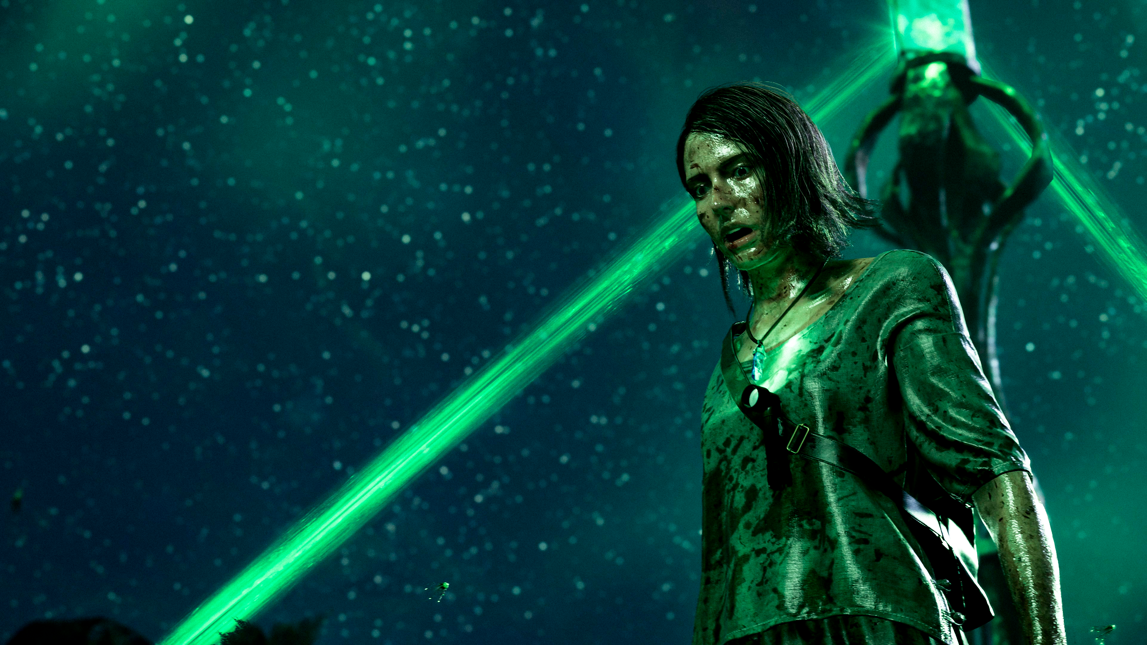 Una donna con una camicia verde in una scena di fantascienza, con luci verdi brillanti.