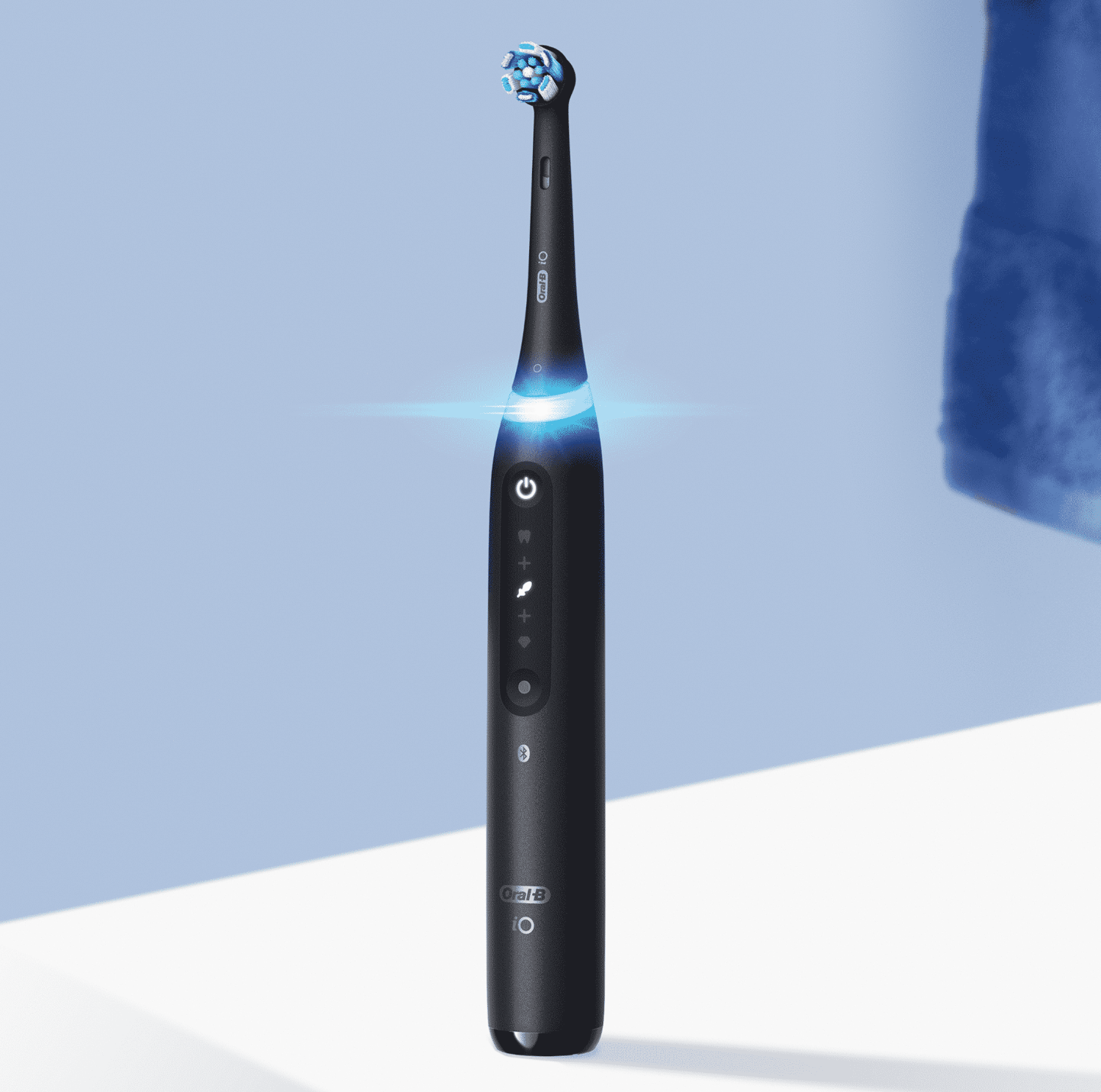 Fekete elektromos fogkefe kék fénnyel, Oral-B márka, kék háttéren.