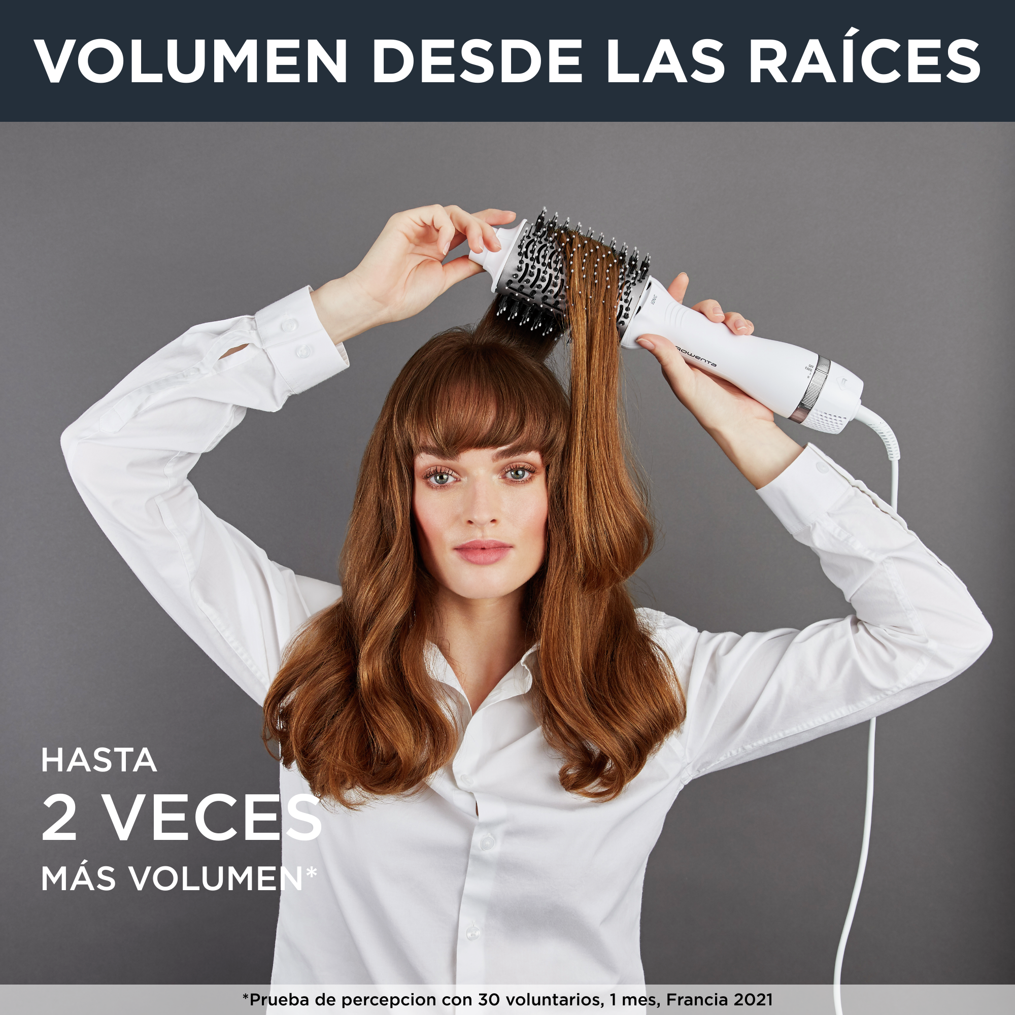 Una mujer peinando su cabello con un moldeador de aire caliente blanco y plateado.