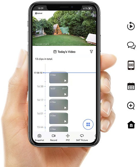 Une main tenant un smartphone. L'écran affiche une chronologie vidéo. Le fond est un jardin vert avec une maison.