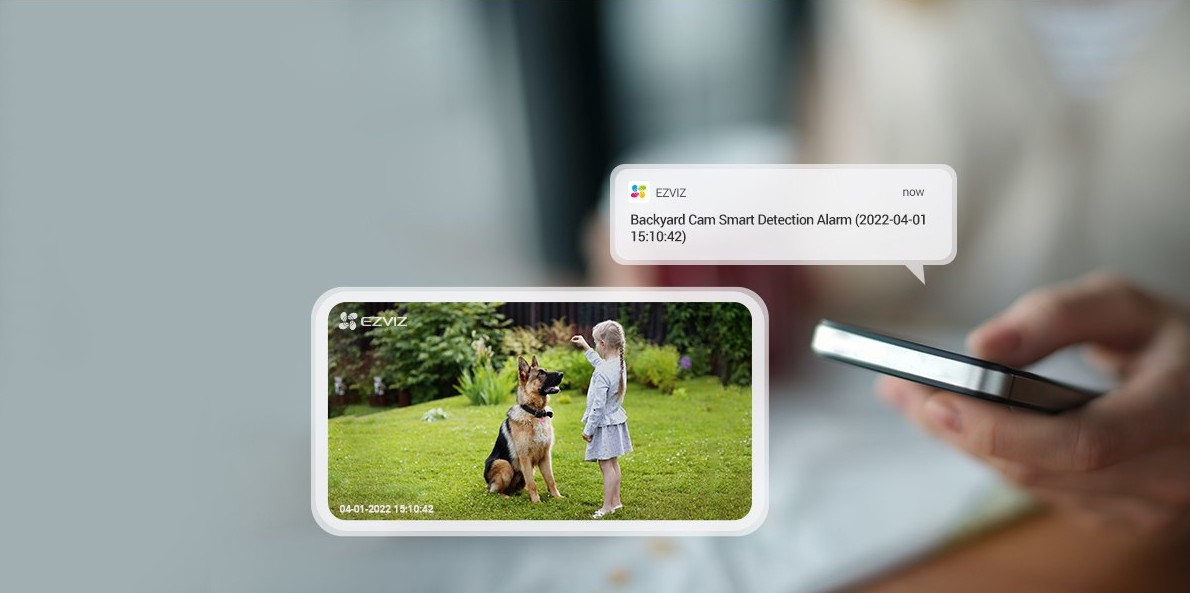 A person holds a phone showing a smart home alert. A dog and girl are on the video. Text bubble nearby.