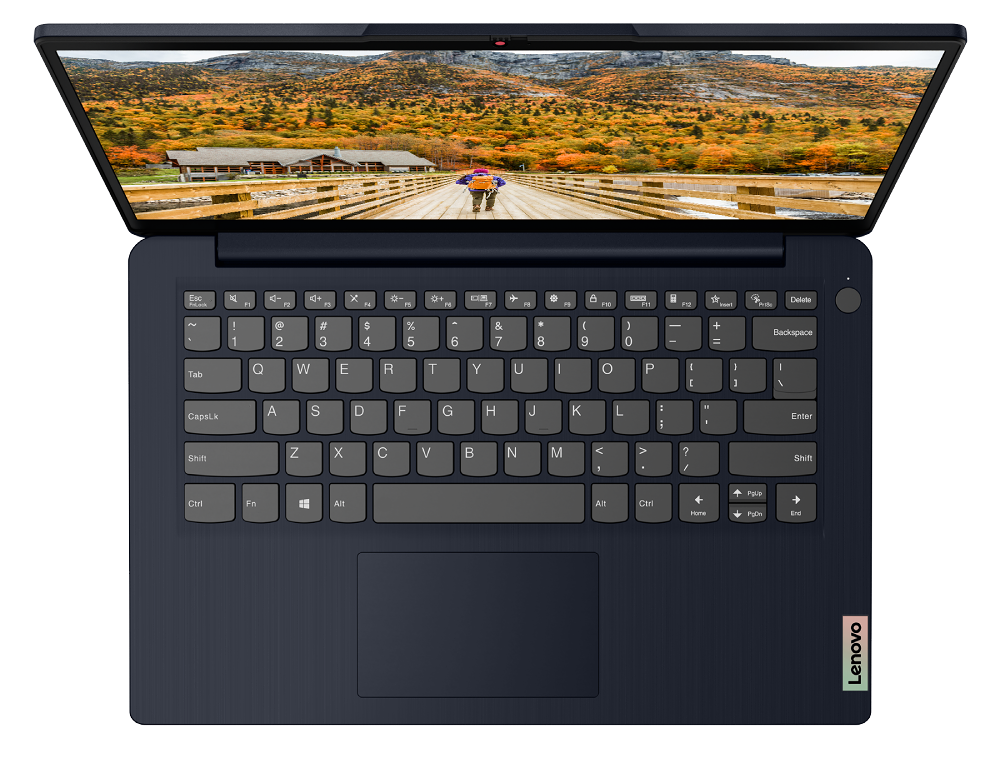Laptop abierto en un escritorio, mostrando una vista de paisaje. Teclado visible, con logo Lenovo rosa.