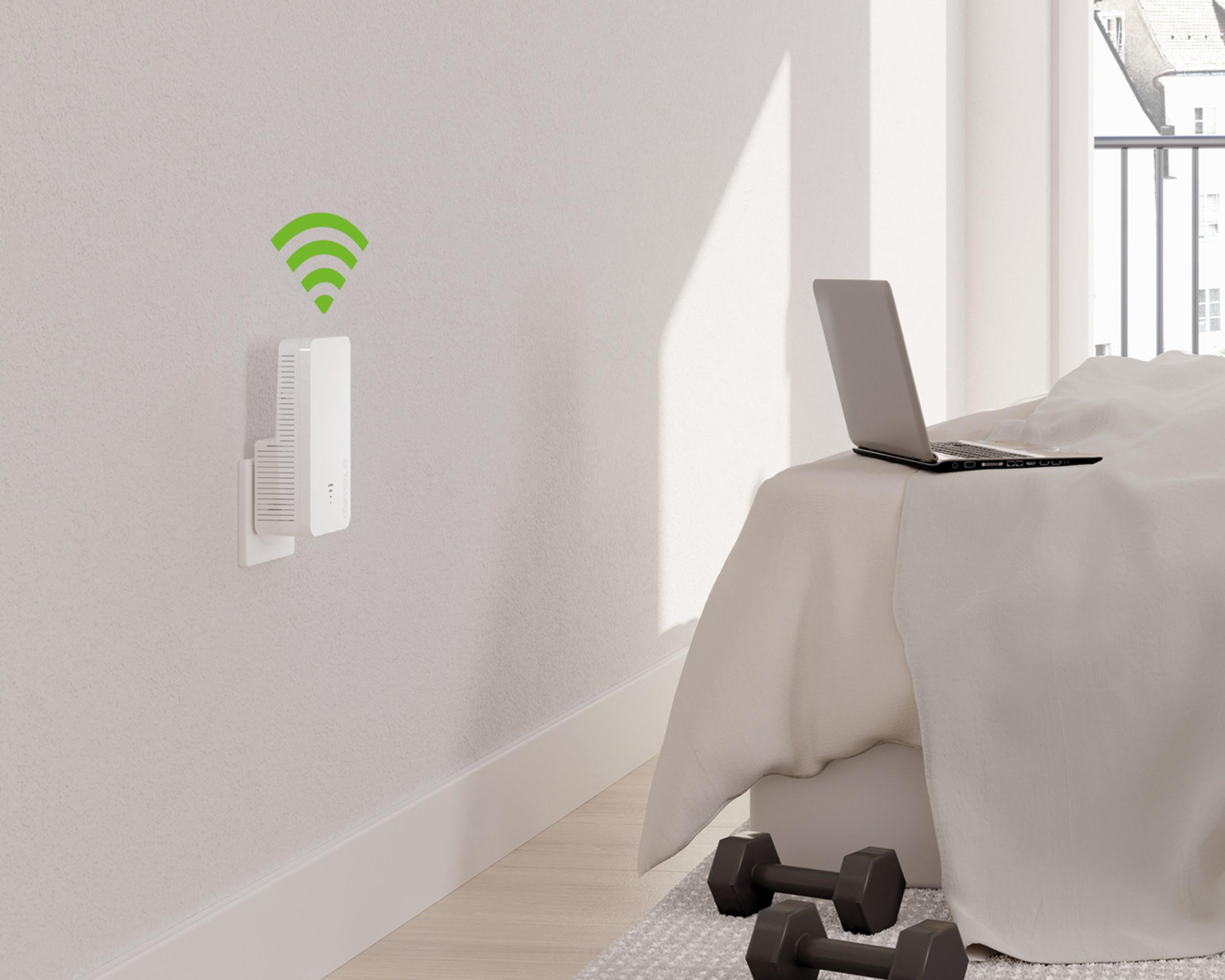 Ein WLAN-Repeater in der Wand, ein Laptop auf einem Bett und Hanteln. Grünes WLAN-Symbol.
