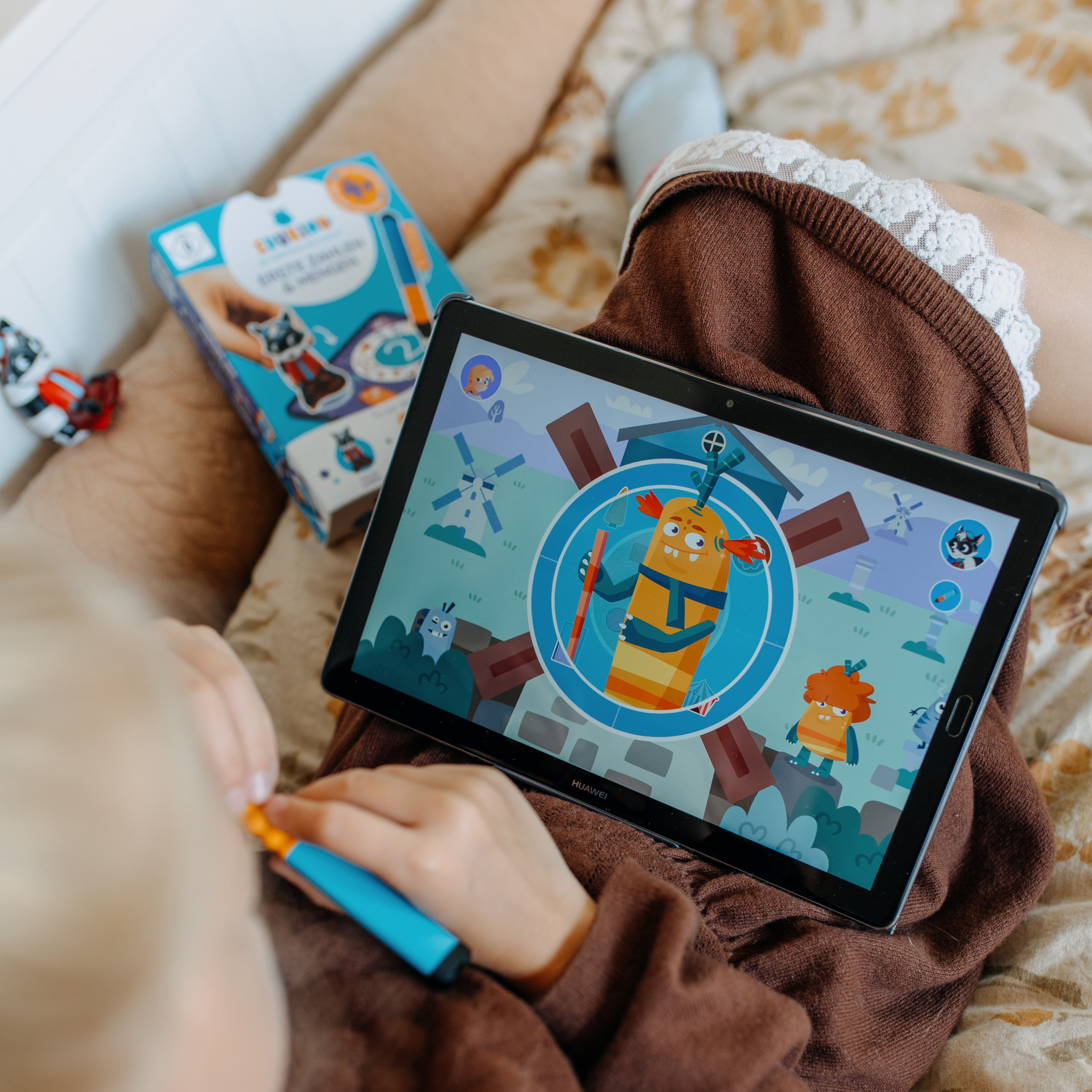 Ein Kind spielt ein Spiel auf einem Tablet. Das Spiel hat einen Zeichentrickcharakter auf dem Bildschirm.