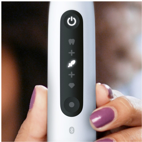 La main d'une personne tenant une brosse à dents électrique blanche, montrant les boutons de commande.