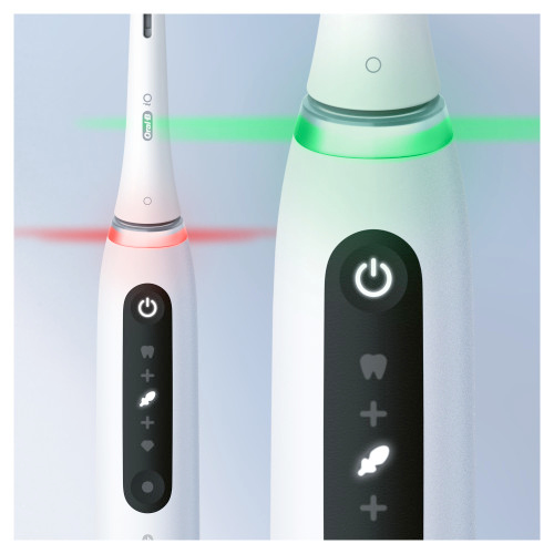 Gros plan sur deux brosses à dents blanches avec des lumières vertes et rouges illuminées sur leurs manches.