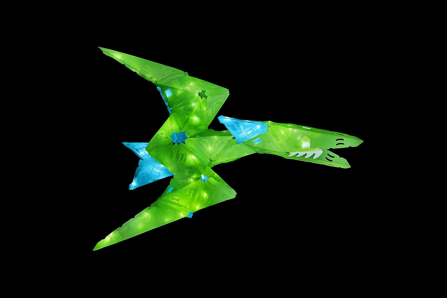 Grünes und blaues Spielzeugflugzeug vor schwarzem Hintergrund.