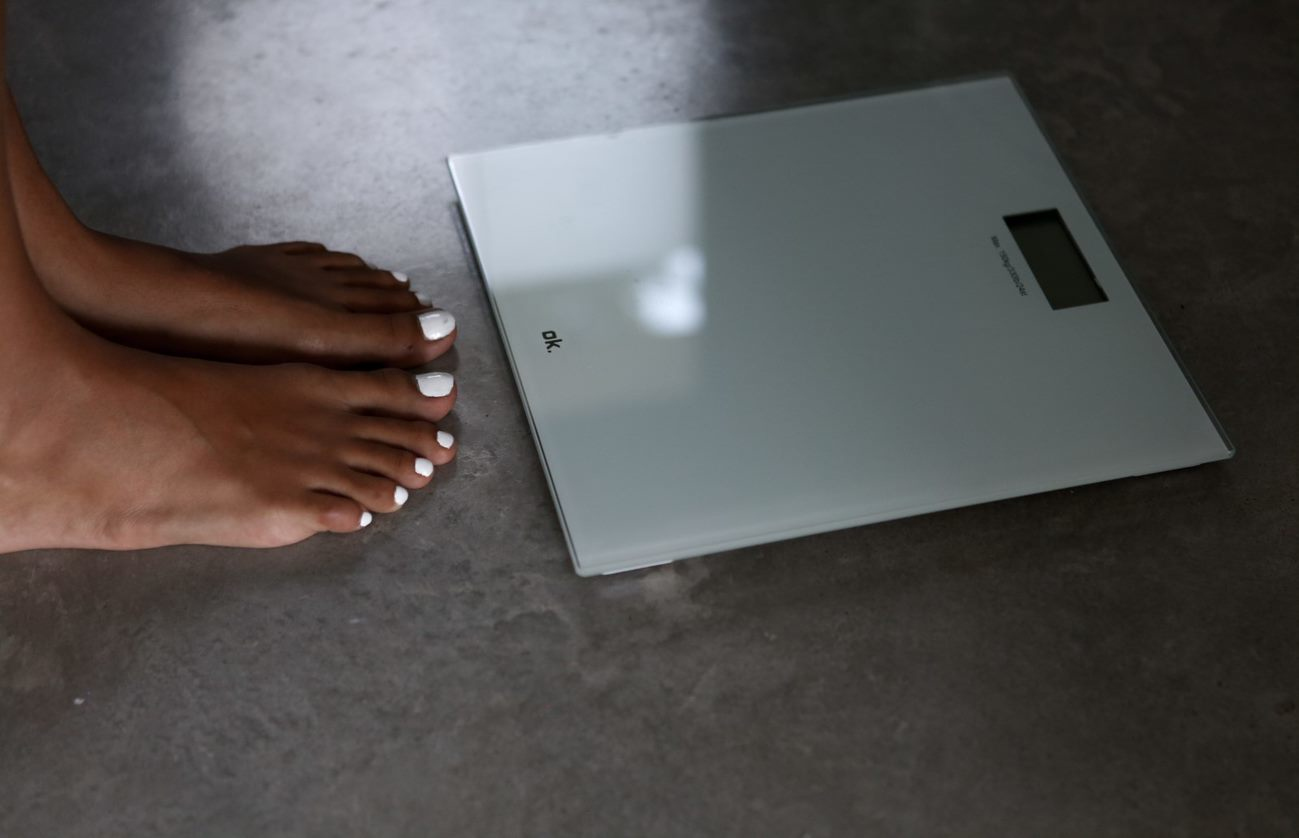 Feet on a white scale on a gray floor.