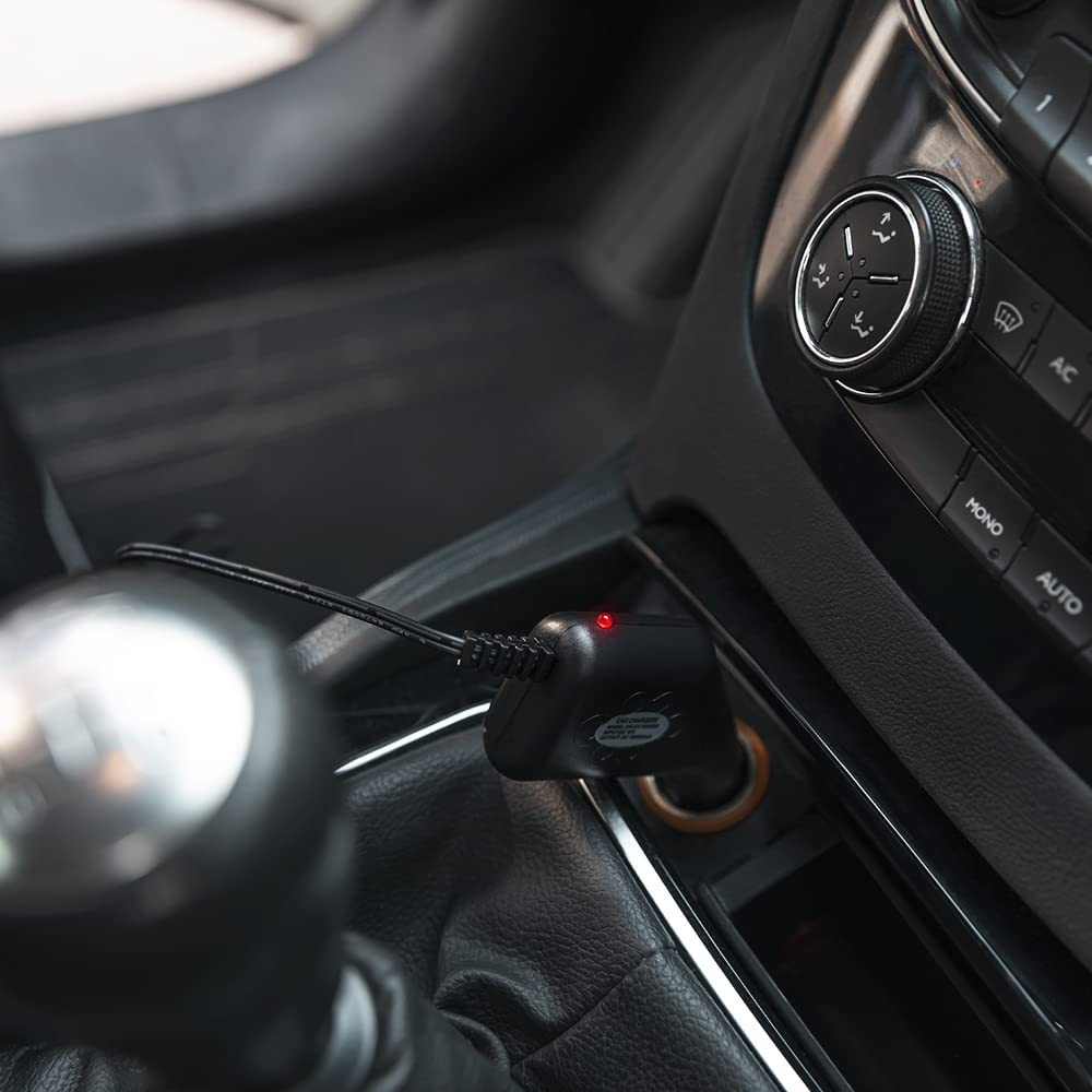 Interior del coche con un cargador conectado al encendedor. Hay una luz roja encendida.