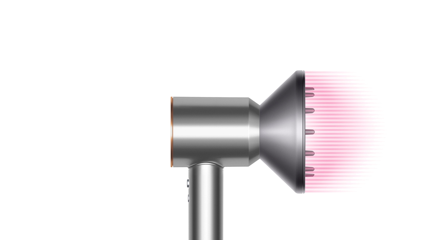 Zilveren en roze Dyson-föhn opzetstuk op zwarte achtergrond.