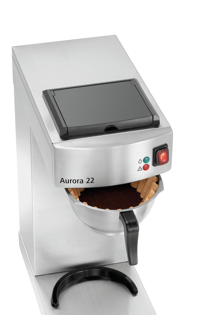 Eine silberne Kaffeemaschine, Modell Aurora 22. Sie hat einen schwarzen Deckel, einen Filter mit Kaffeepulver und einen schwarzen Griff.
