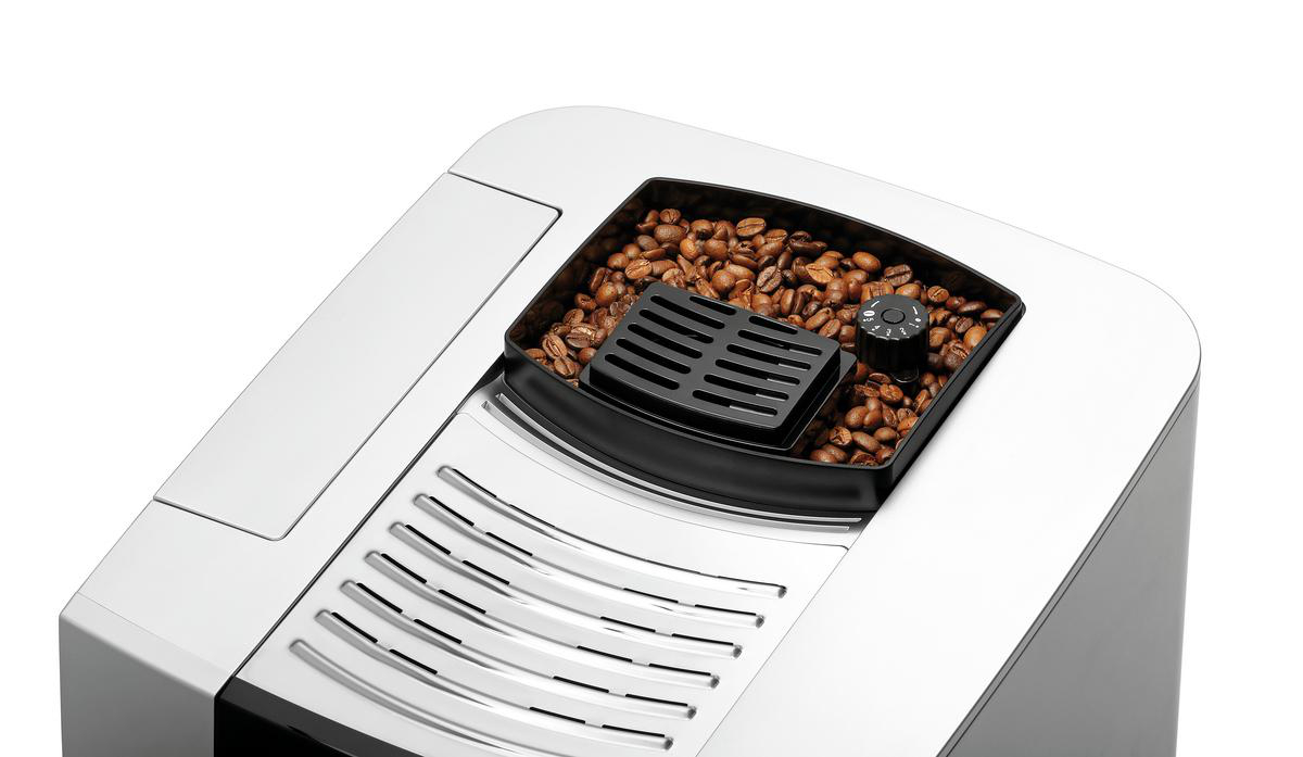 Kaffeebohnen in einem Behälter einer Kaffeemaschine, weißer Hintergrund.