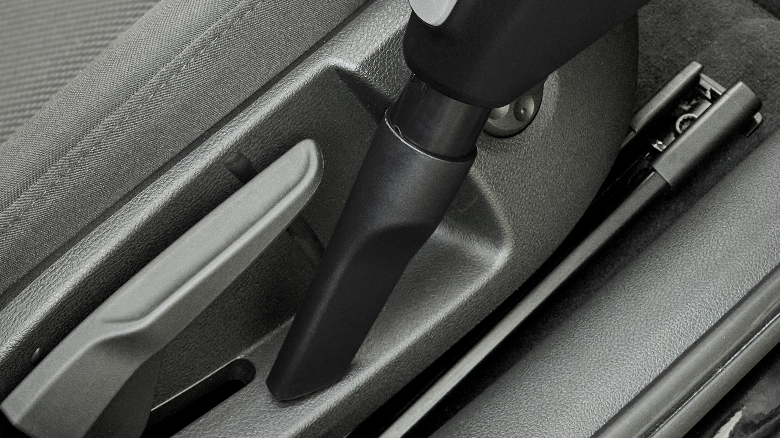 Schwarze Staubsaugerdüse reinigt einen Autositz.
