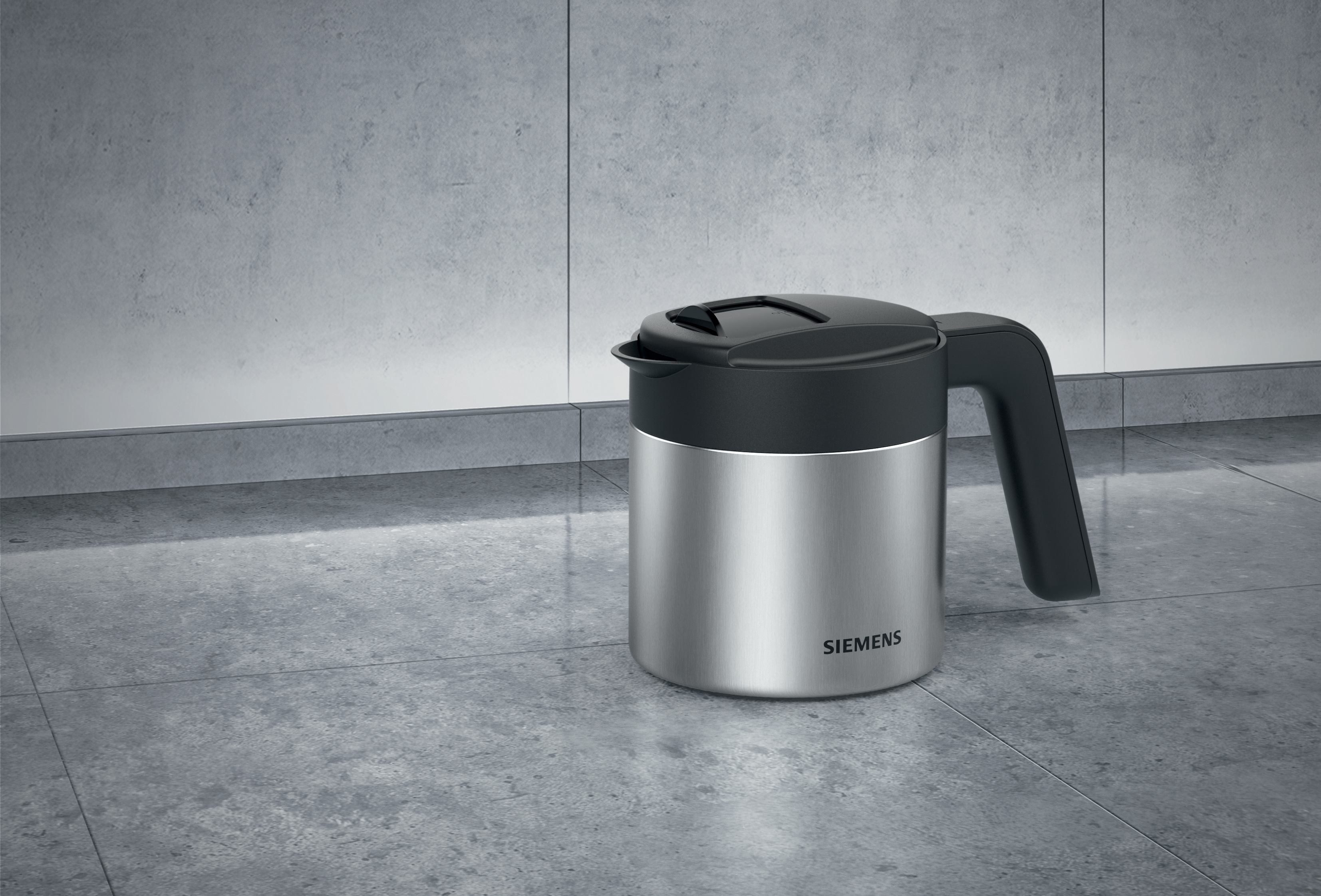 Silberne Siemens Kaffeekanne auf gefliester Oberfläche mit schwarzem Deckel und Griff.