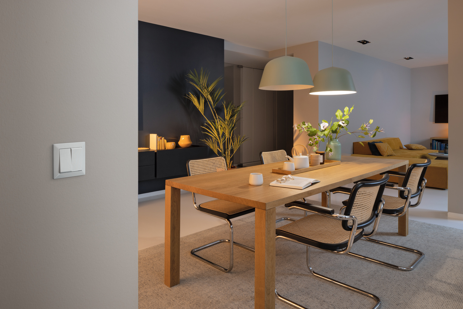 Ein modernes Esszimmer mit Tisch, Stühlen und Beleuchtung.
