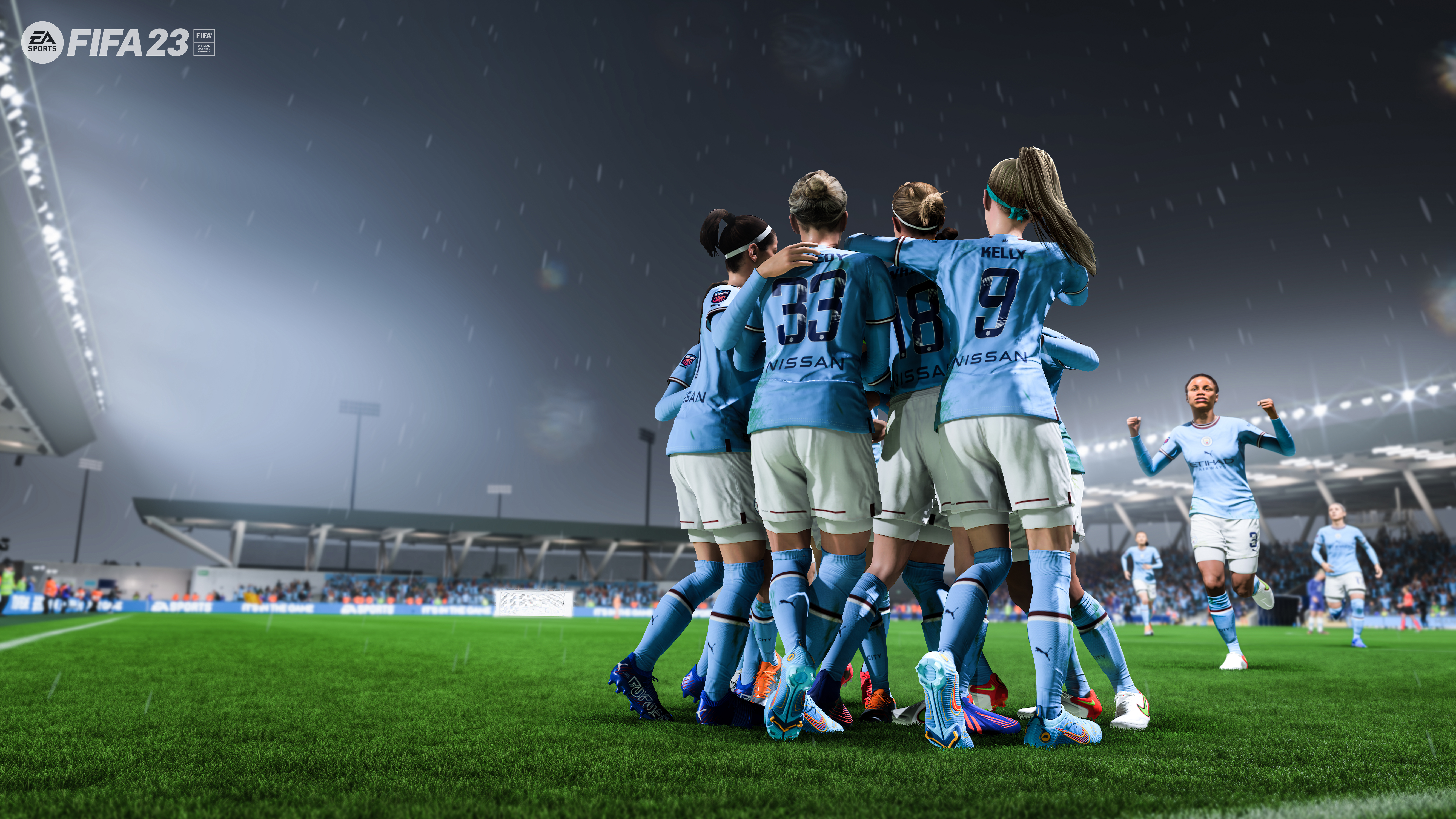 Des joueuses de football en maillots bleu clair célèbrent sur un terrain vert. D'autres joueuses et spectateurs sont visibles en arrière-plan.