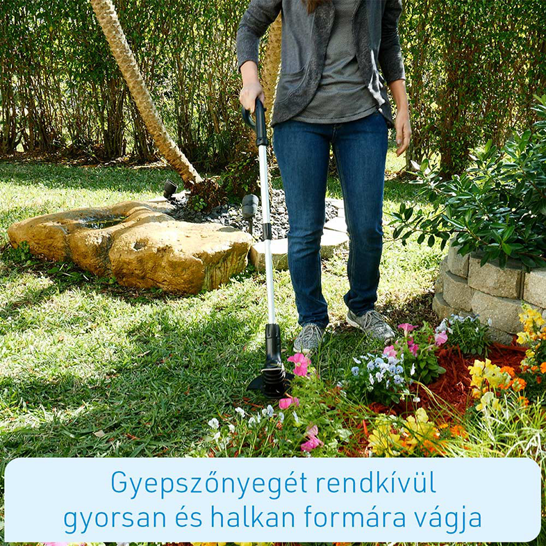 Egy személy fűnyírót használ fű vágásához egy virágokkal teli kertben.